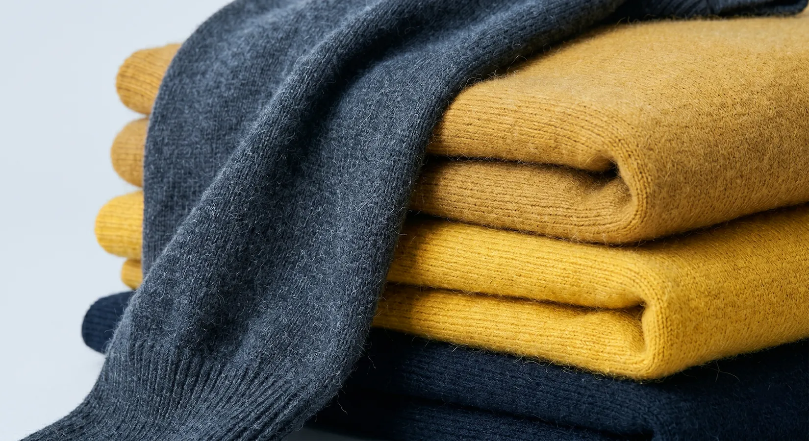 Stack of folded colourful knit sweaters.